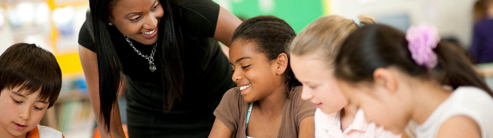 Educator leaning down to engage a group of students