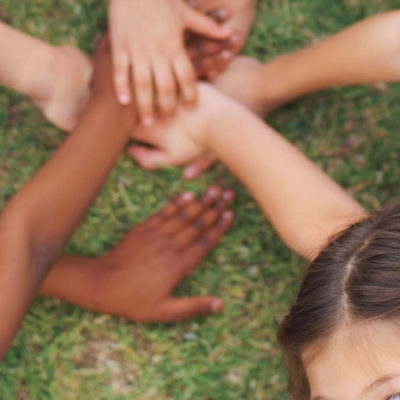 Kids in a circle with their hands in the middle engaged in social emotional learning