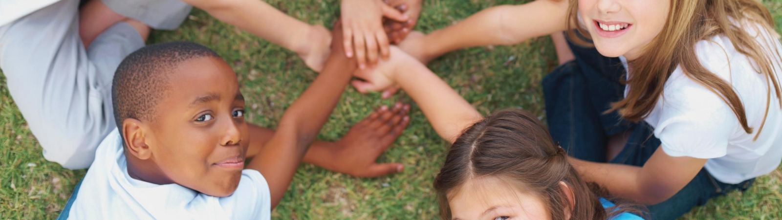 Kids in a circle with their hands in the middle engaged in social emotional learning